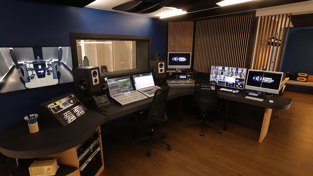 Régie professionnelle de studio podcast : consoles audio, gros monitors, écrans multipistes et contrôle en direct du plateau filmé